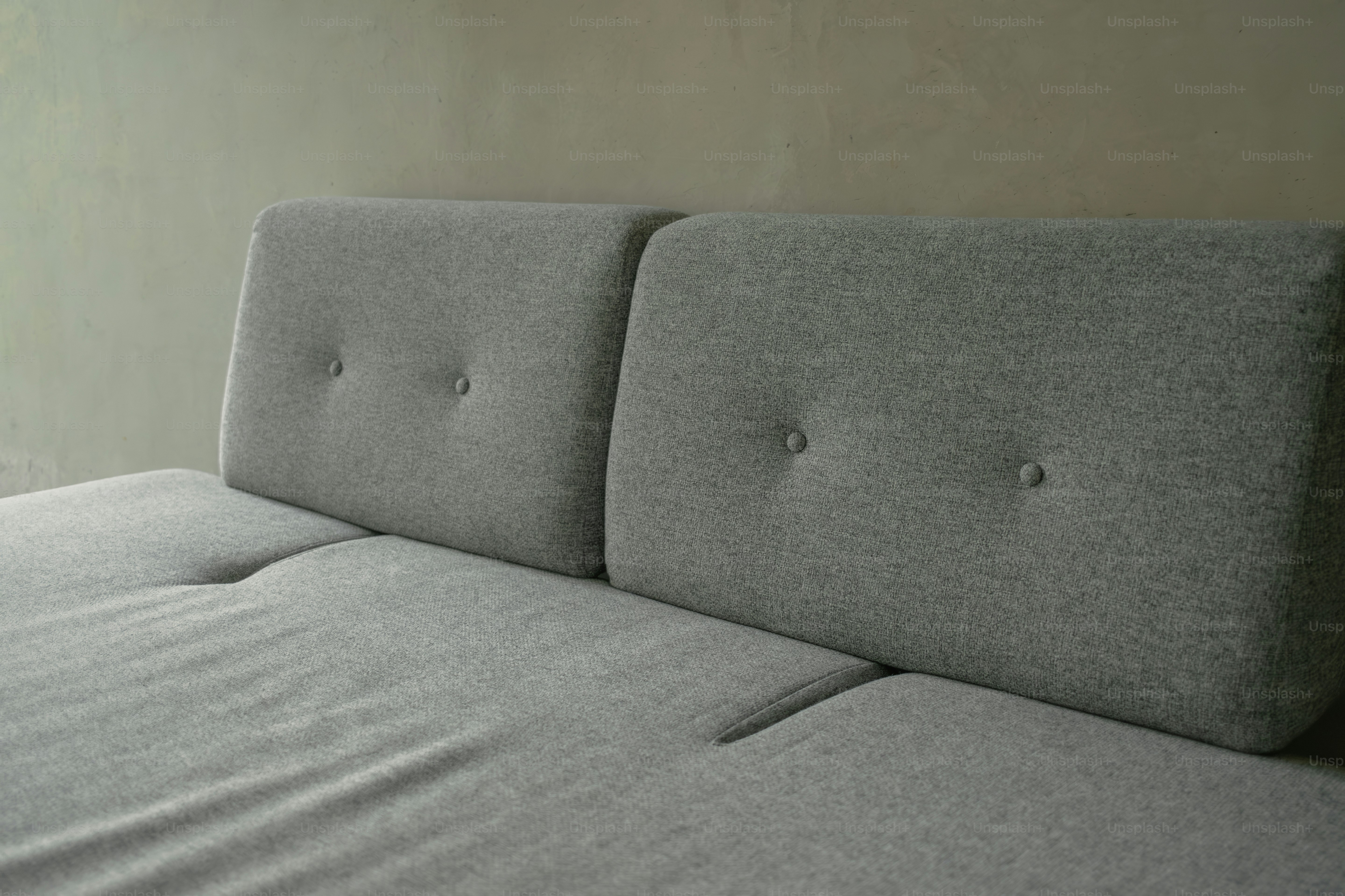 A bed with a gray headboard and a white wall